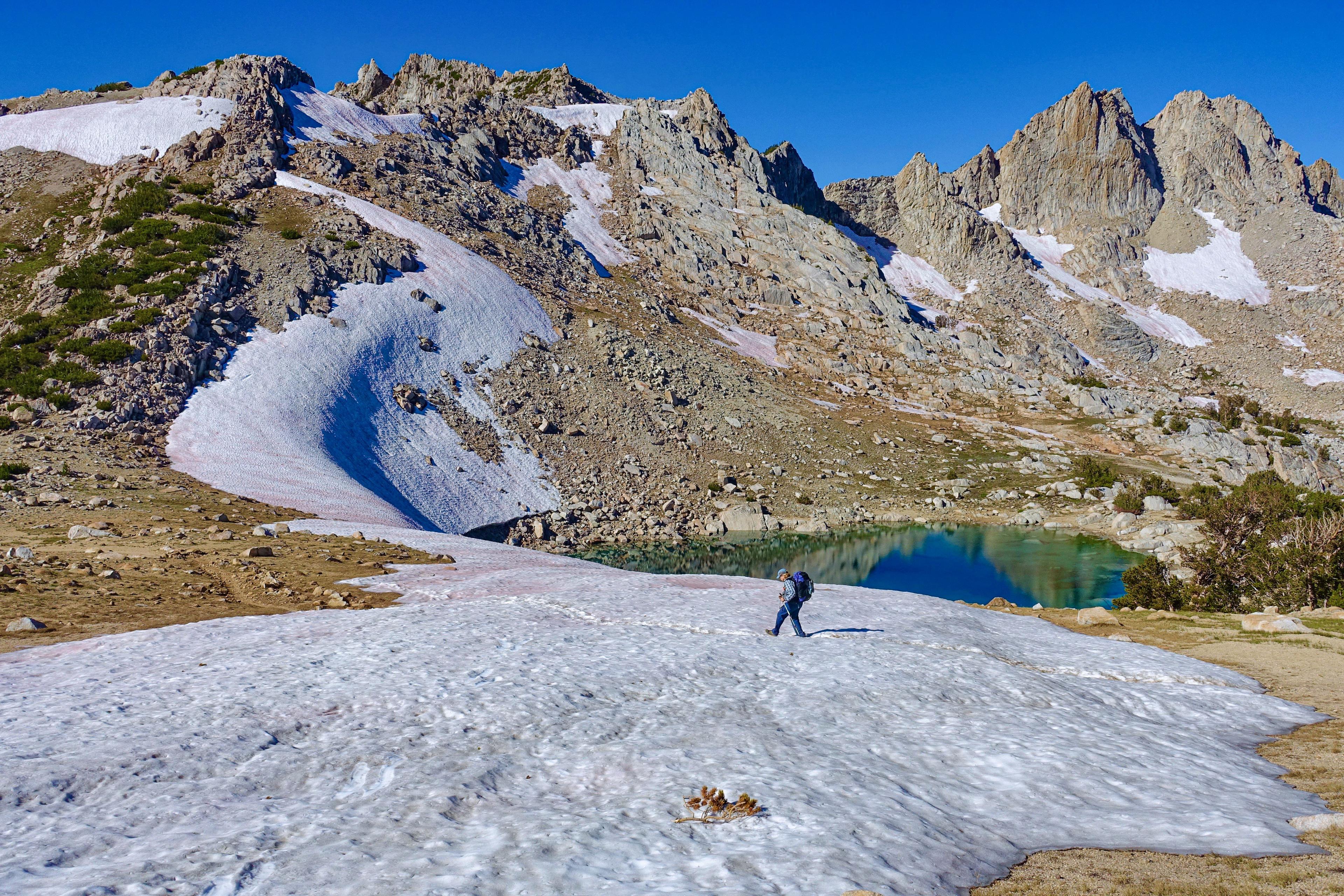 a woman walks on snow in the mountains near a lake